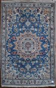 A Persian silk & wool Naiin style rug with central medallion on pale blue ground contained by a