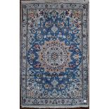 A Persian silk & wool Naiin style rug with central medallion on pale blue ground contained by a