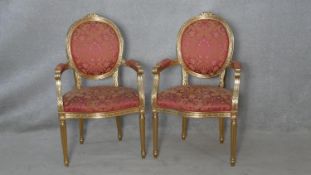 A pair of Louis XVI style gilt framed open armchairs in floral upholstery on fluted tapering