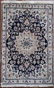 A Persian silk & wool Naiin rug with central floral medallion on a midnight ground within floral