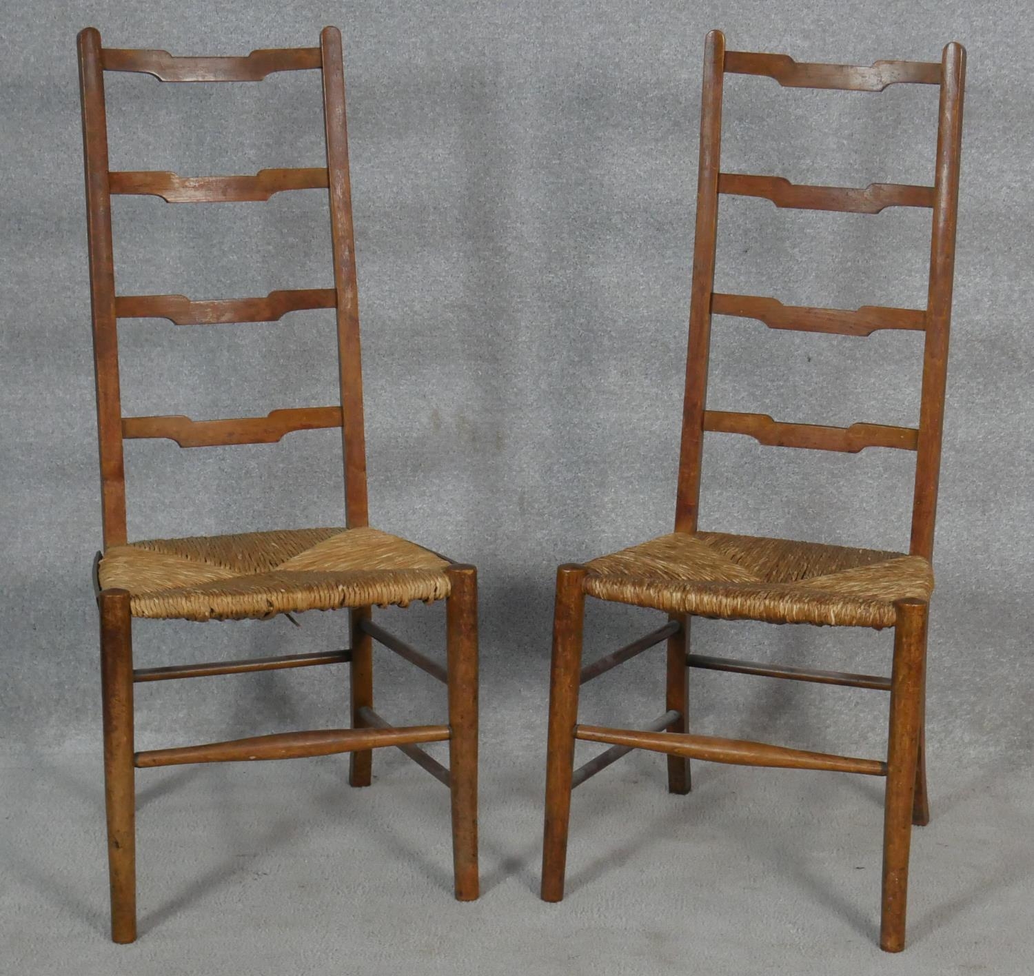 A pair of C.1900 oak ladderback chairs with woven rush seats on circular stretchered supports. H.