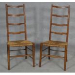 A pair of C.1900 oak ladderback chairs with woven rush seats on circular stretchered supports. H.