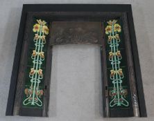 A late 19th century cast iron fire insert with stylised Art Nouveau ceramic tiled lilies flanking