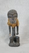 A carved hardwood African tribal figure with coconut husk beard. H.43cm