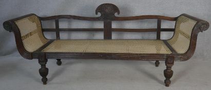 A 19th century Eastern teak double scroll end sofa with carved and reeded frame and caned back and