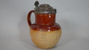 An antique silver lidded Doulton Lambeth tobacco jug with relief decoration. Lid hallmarked: WE,