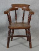 A 19th century elm child's stick back armchair with moulded seat above turned stretchered