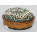 A Victorian mahogany framed footstool in it's original beaded tapestry upholstery on three ceramic