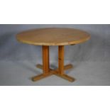 A pine circular kitchen table on quadruped platform supports. H.70 D.120cm