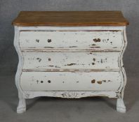 A small distressed painted French bombe style chest with shaped oak top above three long drawers