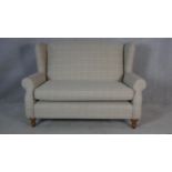A contemporary Georgian style two seater wing back sofa in window pane upholstery on turned tapering