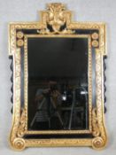 An early Georgian style parcel gilt and lacquered pier mirror with carved foliate cresting and