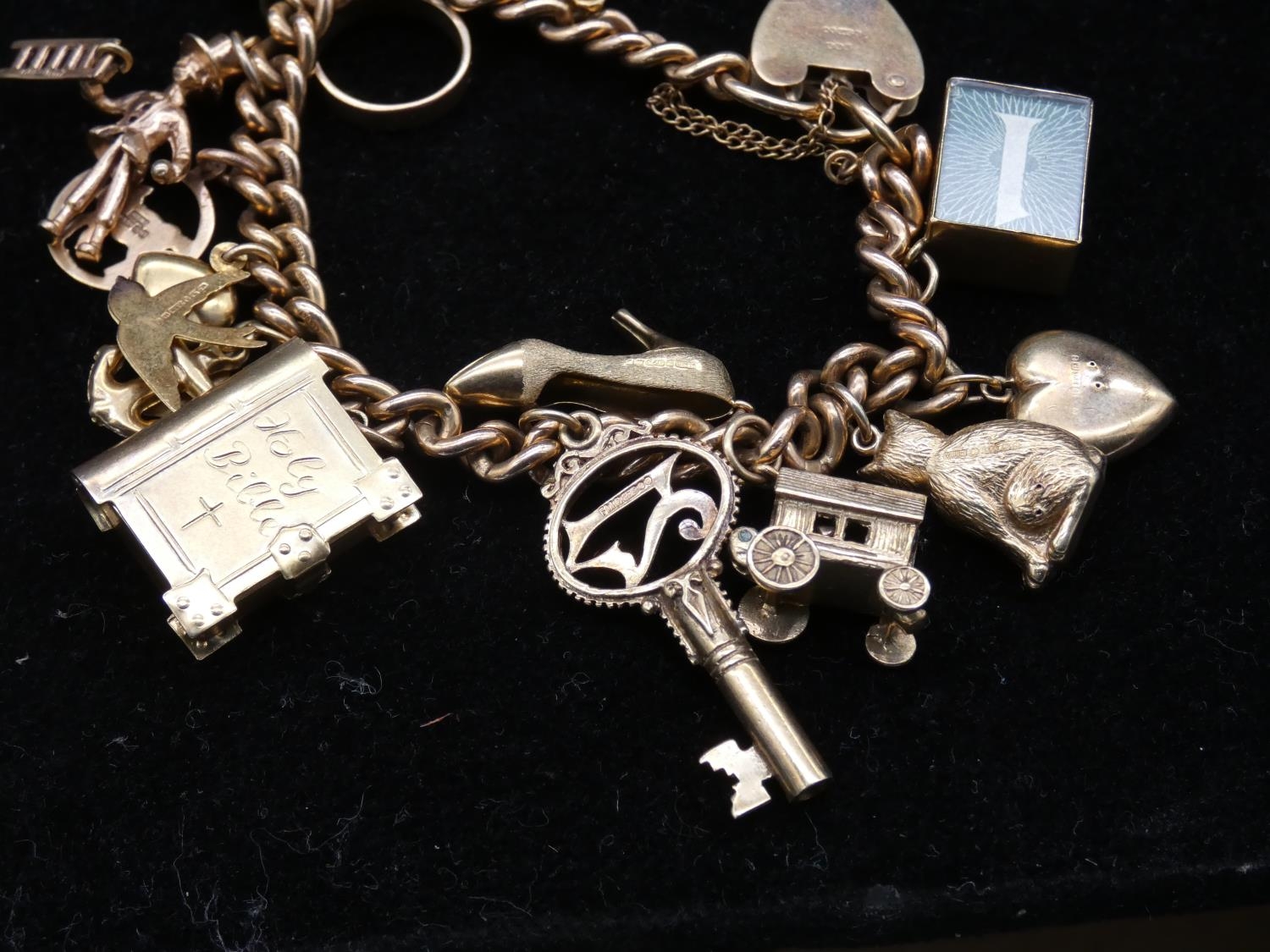 A vintage solid curb link 9ct gold charm bracelet with fifteen 9ct yellow gold charms. The charms - Image 4 of 14