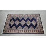 An Eastern rug with repeating lozenge medallions on midnight ground within stylised foliate multi