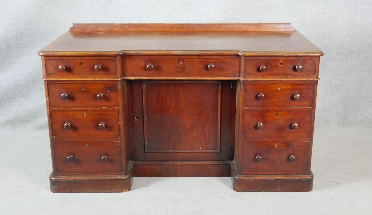 A 19th century mahogany pedestal desk with an arrangement of drawers and kneehole cupboard on plinth