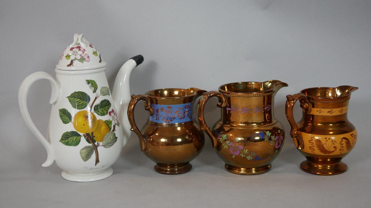 Three antique copper lustre ware pitchers along with a Port Merion Pomona design coffee pot with