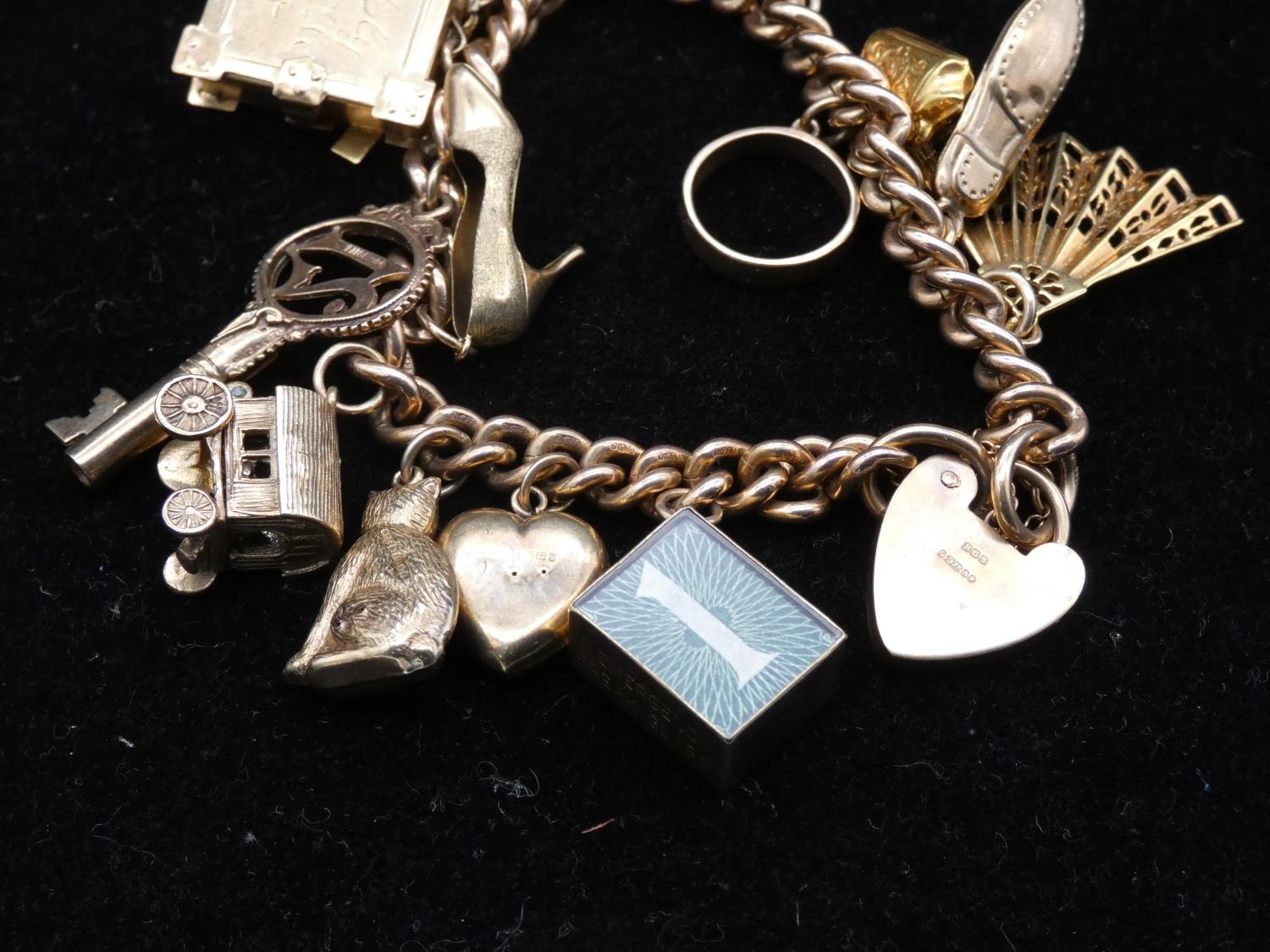 A vintage solid curb link 9ct gold charm bracelet with fifteen 9ct yellow gold charms. The charms - Image 5 of 14