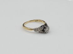 An Edwardian 18 carat gold and platinum flanked solitaire Diamond ring with foliate design