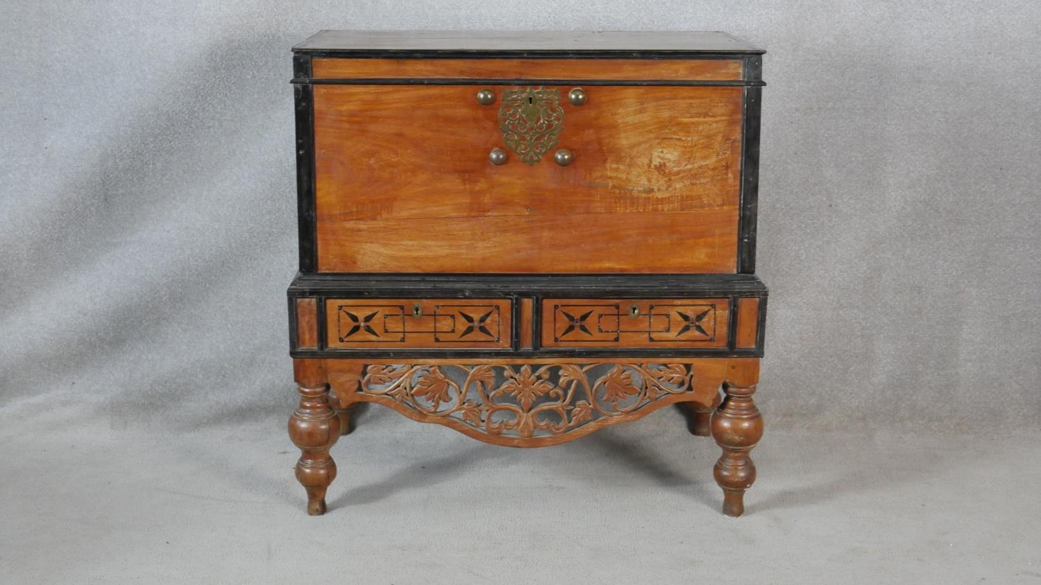 A Nineteenth Century Ceylonese hardwood and ebonised coffer on carved stand fitted with two base