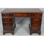 A Georgian style flame mahogany pedestal desk with inset gilt tooled leather top above an