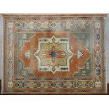A Turkish Anatolian carpet with central medallion on salmon ground within stylised geometric