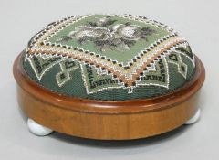 A Victorian mahogany framed footstool in it's original beaded tapestry upholstery on three ceramic