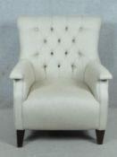 A contemporary tub armchair in buttoned and piped upholstery on tapering block supports. H.97 W.80