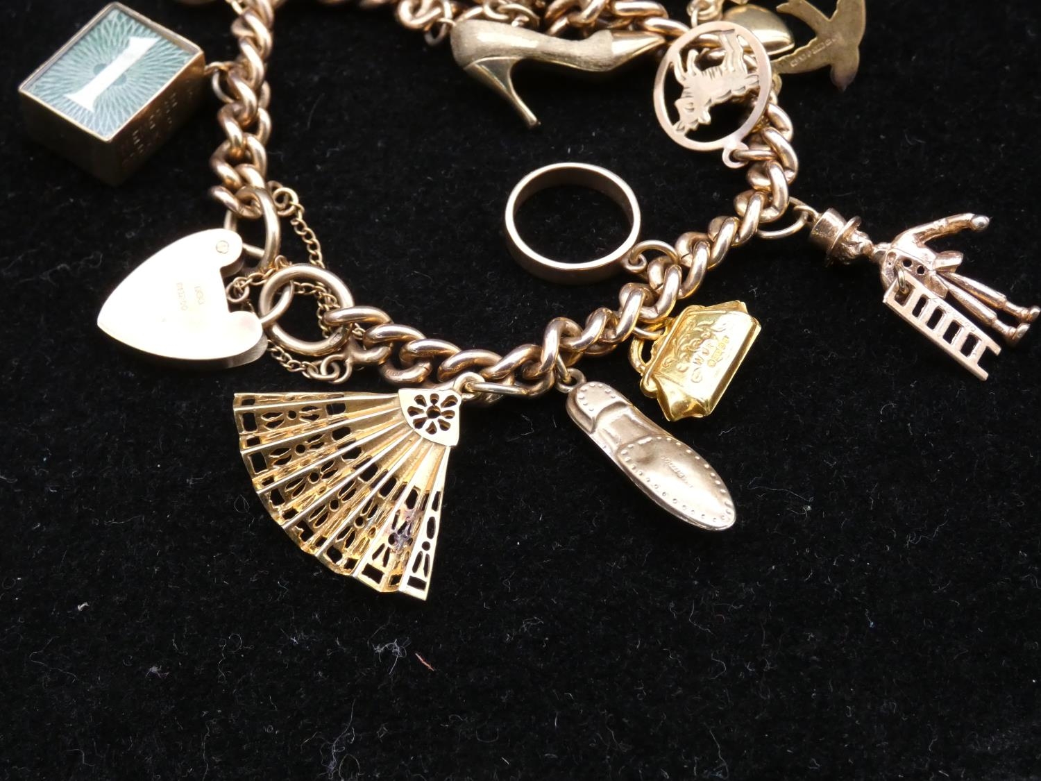 A vintage solid curb link 9ct gold charm bracelet with fifteen 9ct yellow gold charms. The charms - Image 2 of 14