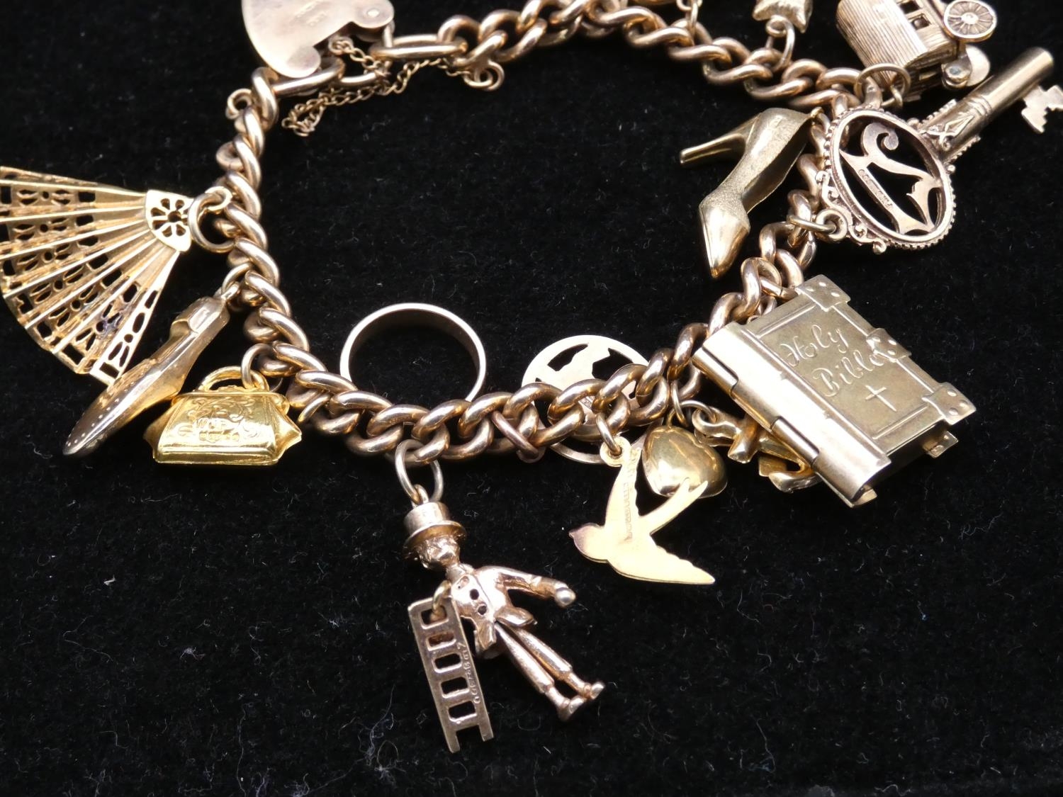 A vintage solid curb link 9ct gold charm bracelet with fifteen 9ct yellow gold charms. The charms - Image 3 of 14