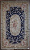 A needlepoint rug with central floral oval medallion on a midnight field contained by foliate