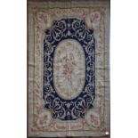 A needlepoint rug with central floral oval medallion on a midnight field contained by foliate