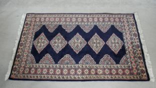 An Eastern rug with repeating lozenge medallions on midnight ground within stylised foliate multi