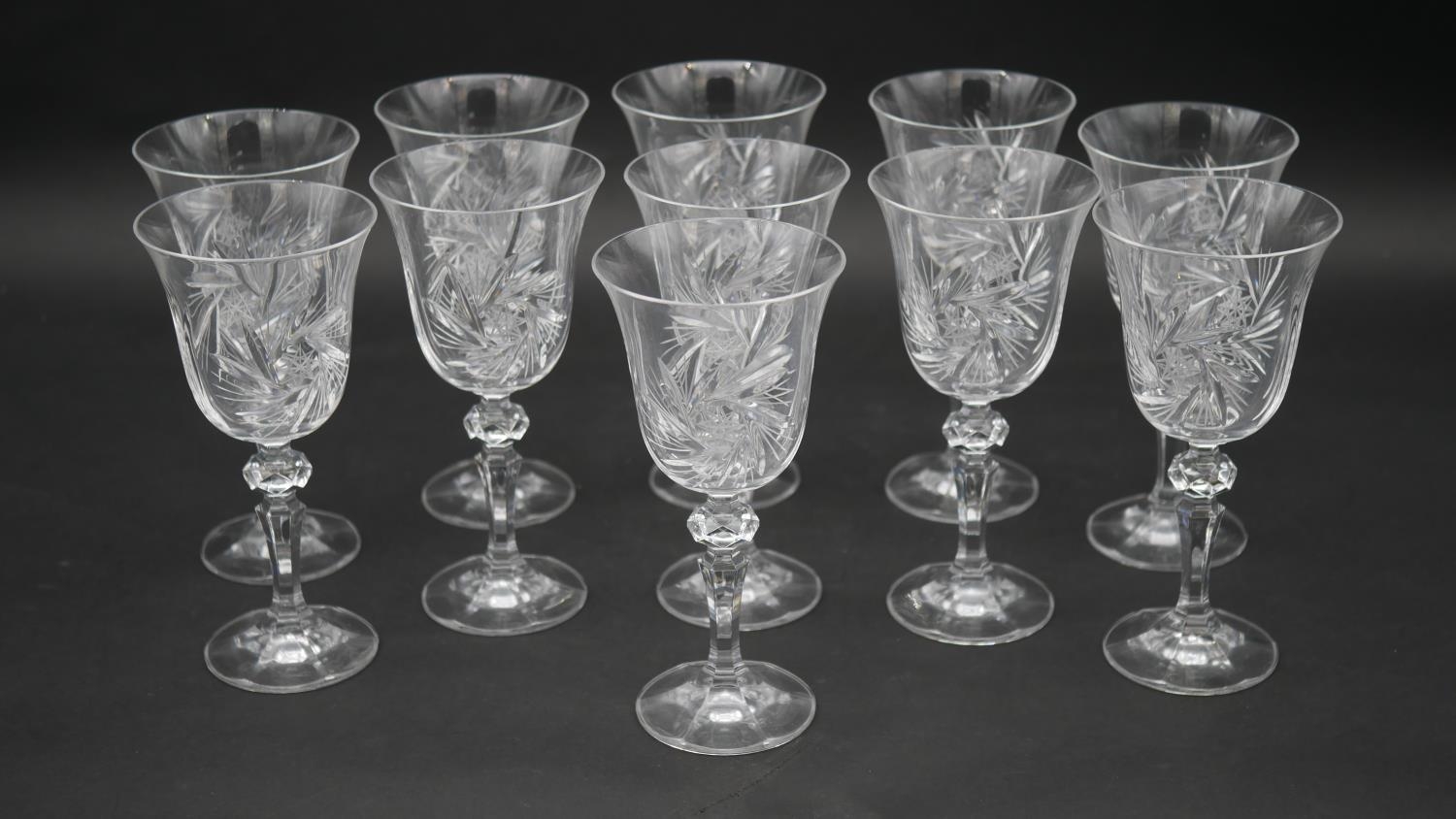 A set of eleven engraved and cut crystal wine glasses with star design and faceted stems. H.17.5cm