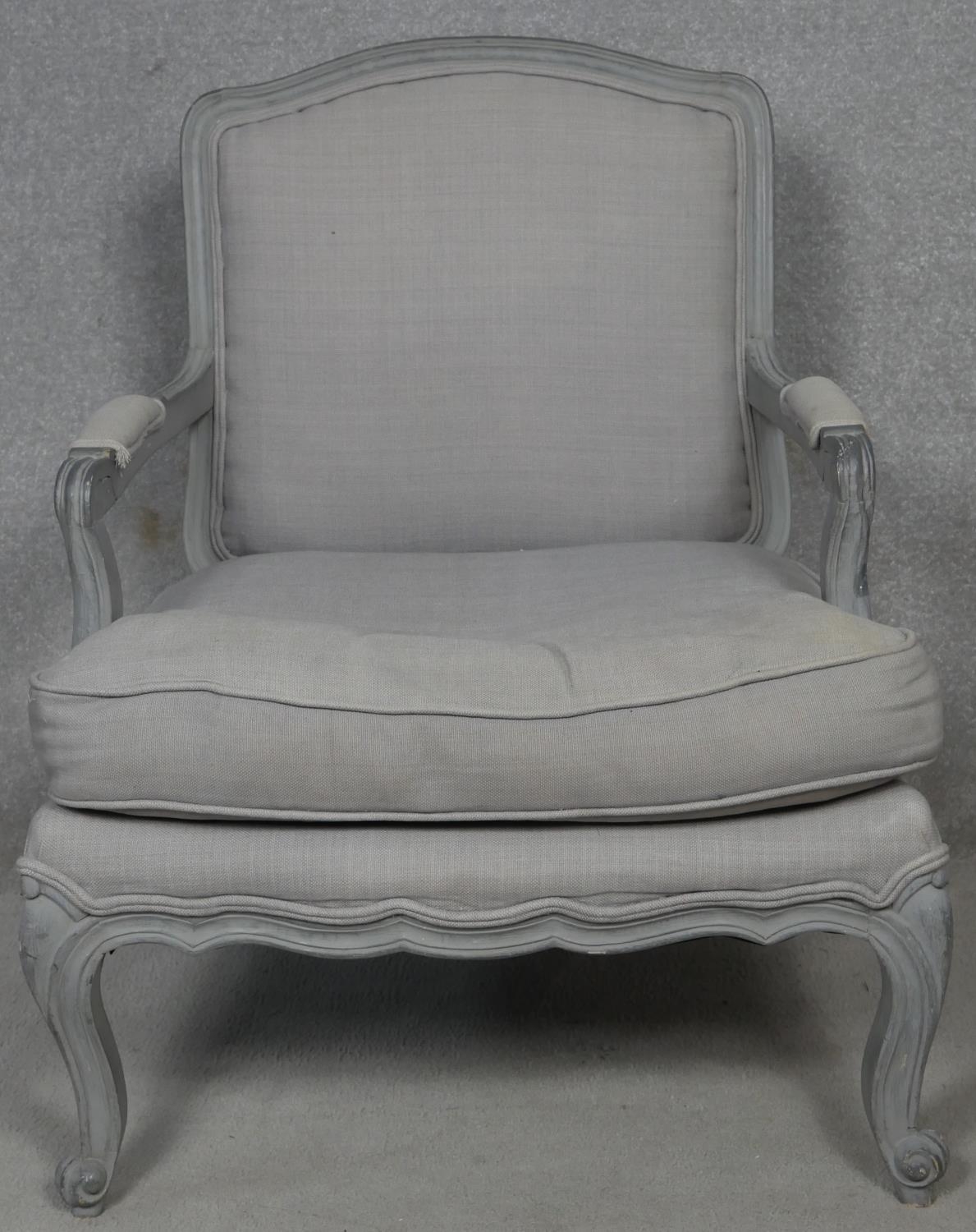 A painted Louis XV style armchair in double piped calico upholstery on carved scrolling cabriole