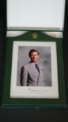 A presentation photograph of HRH Prince Charles in green leather frame with gilt Prince of Wales