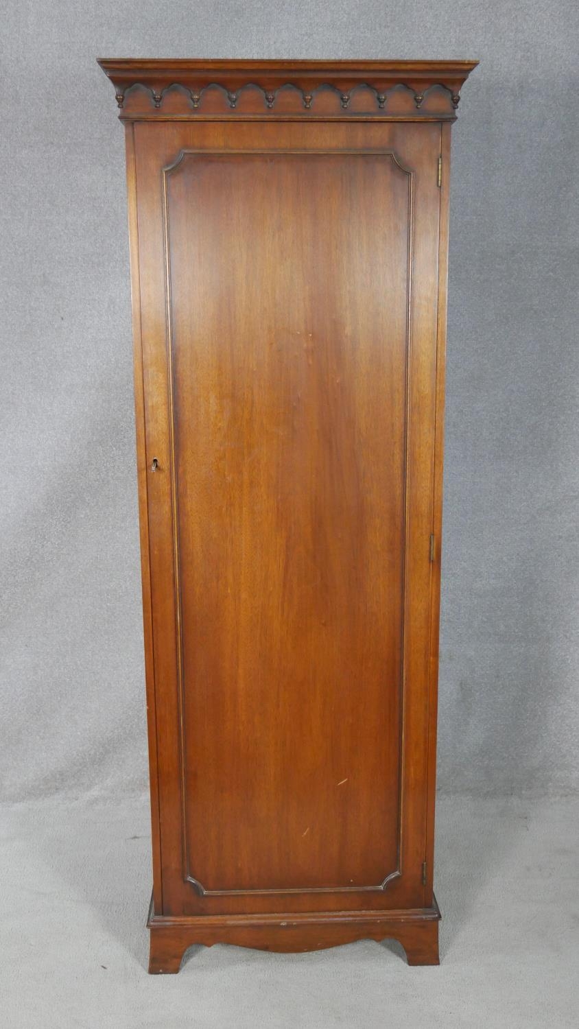 A Georgian style mahogany hall cupboard with panel door enclosing hanging space on shaped bracket