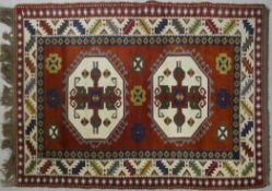 A Turkish Kars rug with double hooked medallions on a burgundy ground within stylised serrated