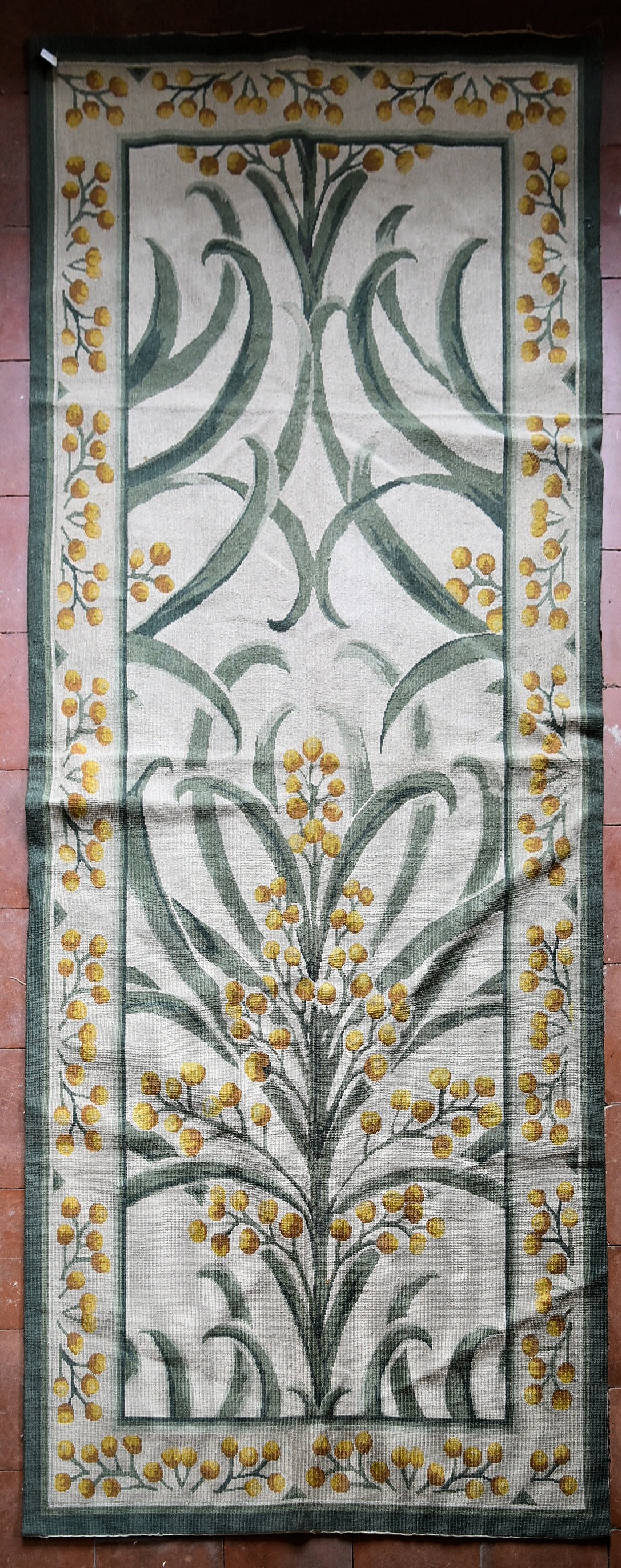 A needlepoint rug with a stylised scrolling flowering mimosa design to the central field and border.