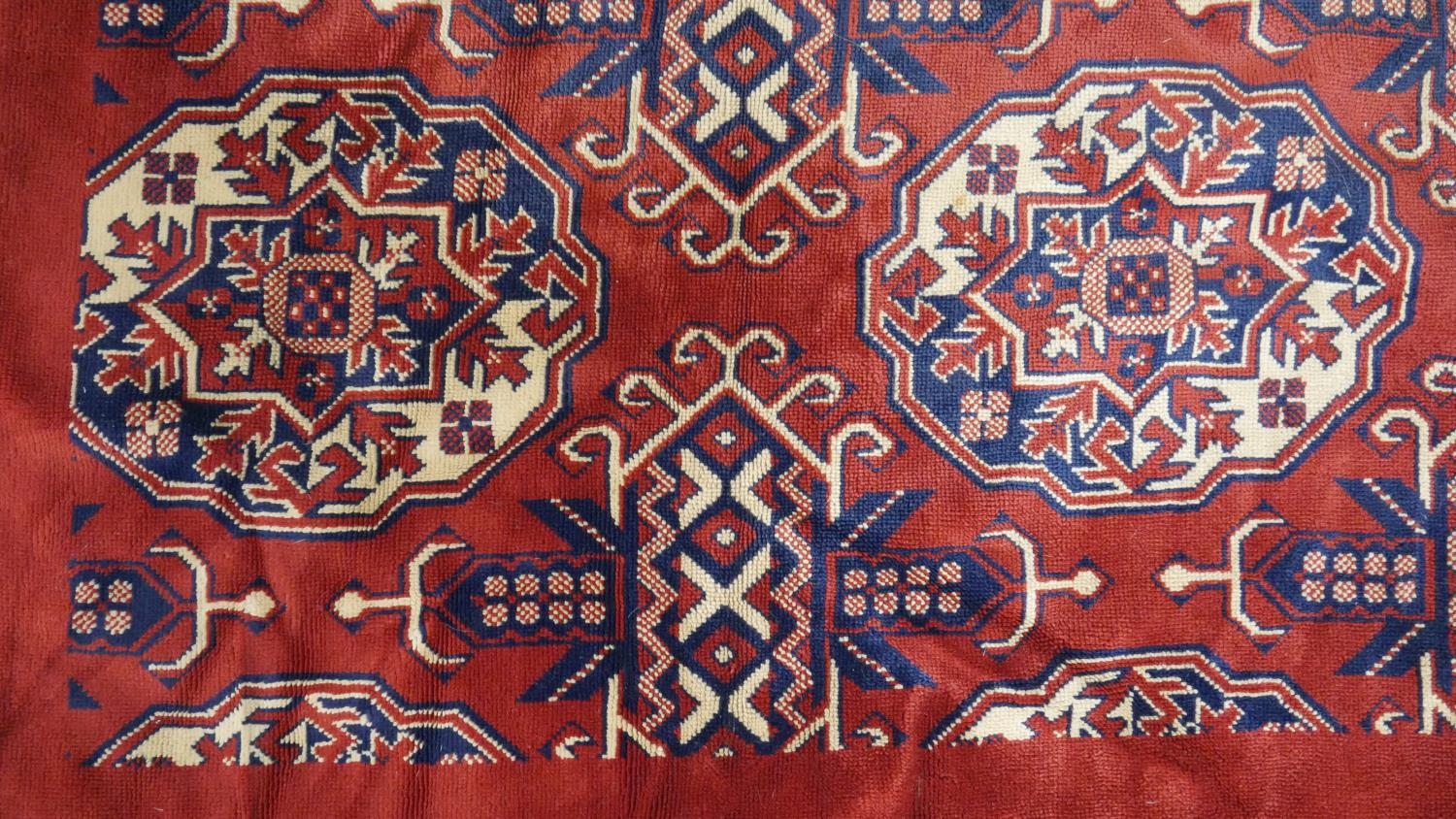 A Bokhara style carpet with repeating gull motifs on a madder field in a plain border along with a - Image 3 of 11