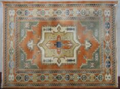 A Turkish Anatolian carpet with central medallion on salmon ground within stylised geometric