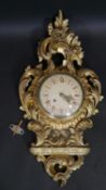 A Swedish Rococo carved giltwood cartel clock by Exacta with white enamel dial and Roman numerals.