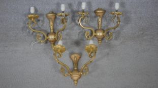 A set of three gilt metal twin branch wall sconces with scrolling arms and crystal drops. W.27cm