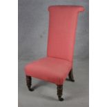 A 19th century upholstered nursing chair on tapering oak turned supports terminating in brass cup