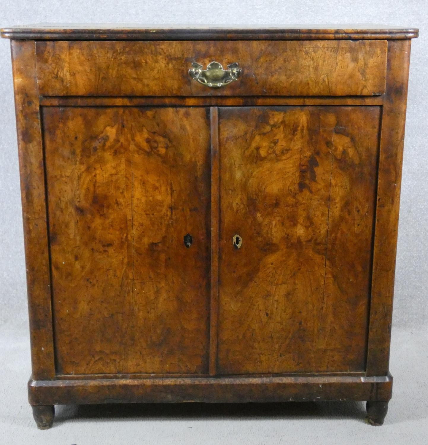 A late 19th century Continental burr walnut chiffonier with frieze drawer above panel doors on