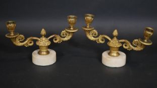 A pair of 19th century gilt metal twin branch candelabras with scrolling cornucopia arms on marble