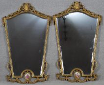 A pair of French style gilt gesso framed wall mirrors with shaped bevelled plates in reeded ribbon