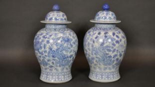 A pair of Chinese blue and white lidded temple jars with all over foliate, lotus flower and dragon