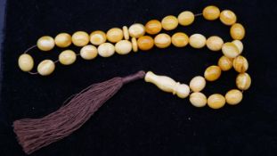 A string of thirty six marble white Baltic amber worry beads with silk tassel. Weight 30.7g L.38cm.