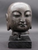 A carved stone Buddha's head on stand. H.29cm