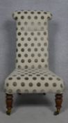 A 19th century upholstered nursing chair on oak turned supports terminating in brass cup casters.